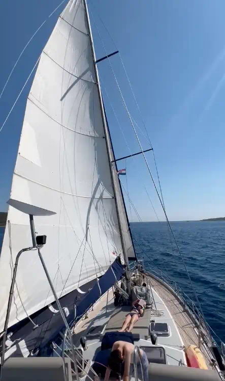 Voilier en navigation en Grèce avec voiles déployées et passagers se relaxant à bord