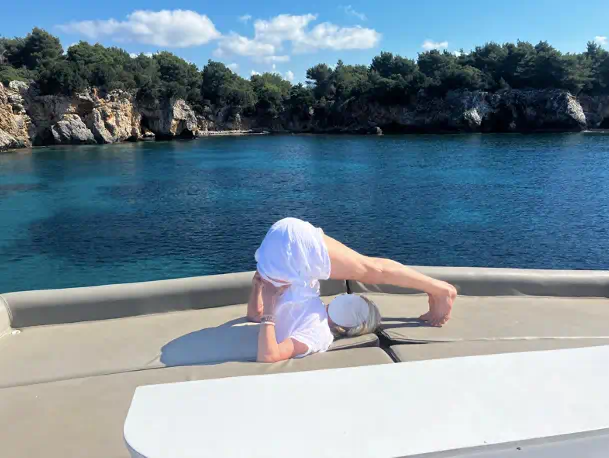 femme en posture de yoga sur un voilier en Grece dans une baie calme
