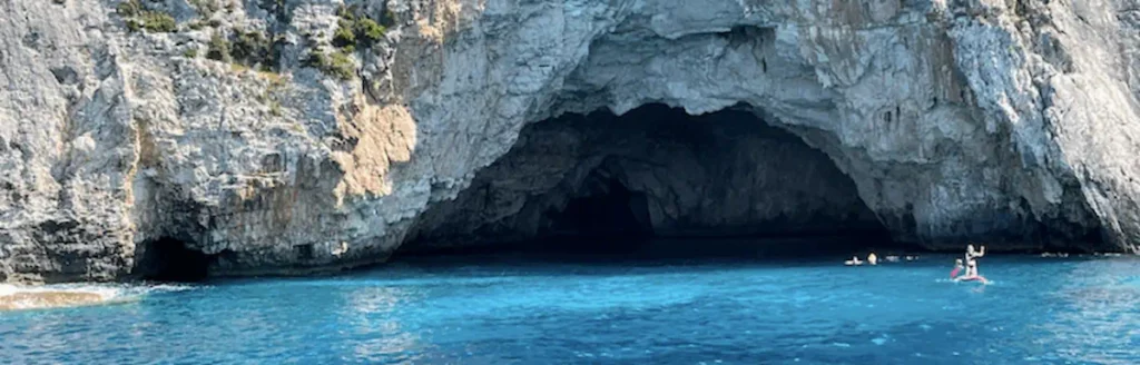 Baignade d’enfants dans une grotte aux eaux calmes lors d’une croisière en famille en voilier en Grèce