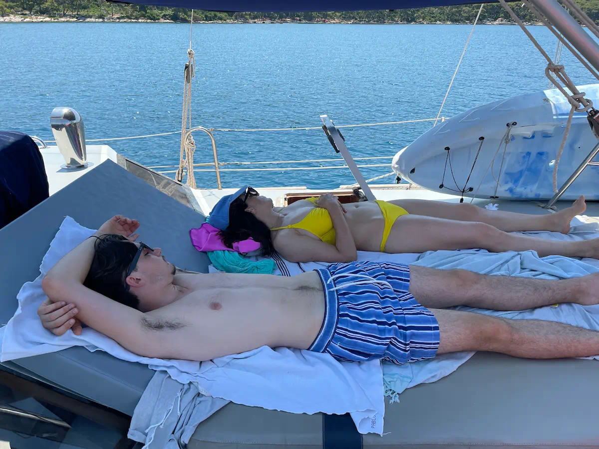 Personnes allongées sur les lits extérieurs du voilier Najida au mouillage