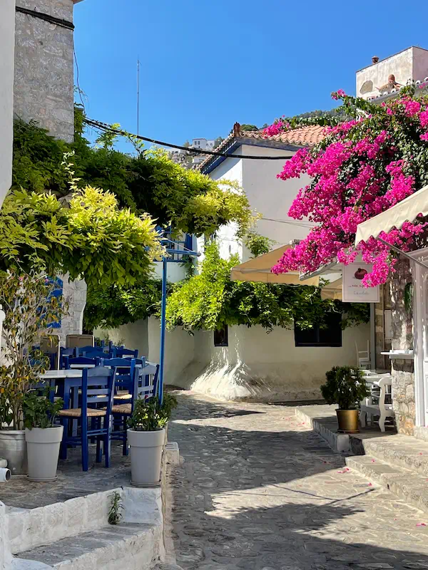 Ruelle d’un village grec avec bougainvilliers et terrasse de taverne