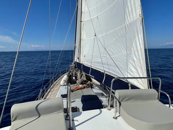 Passagère se relaxant sur le pont d’un voilier en navigation en Grèce avec skipper
